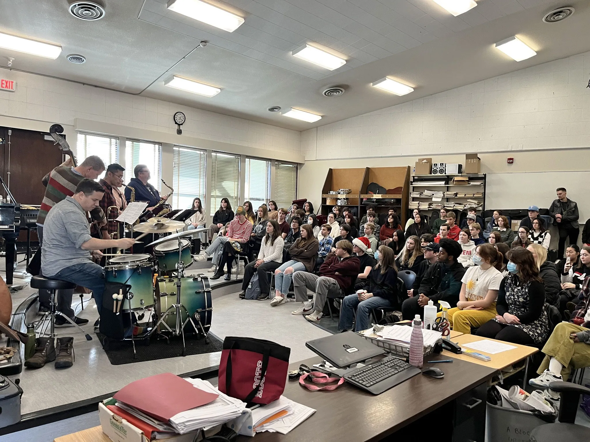 A jazz trio performs for high school students in a music room