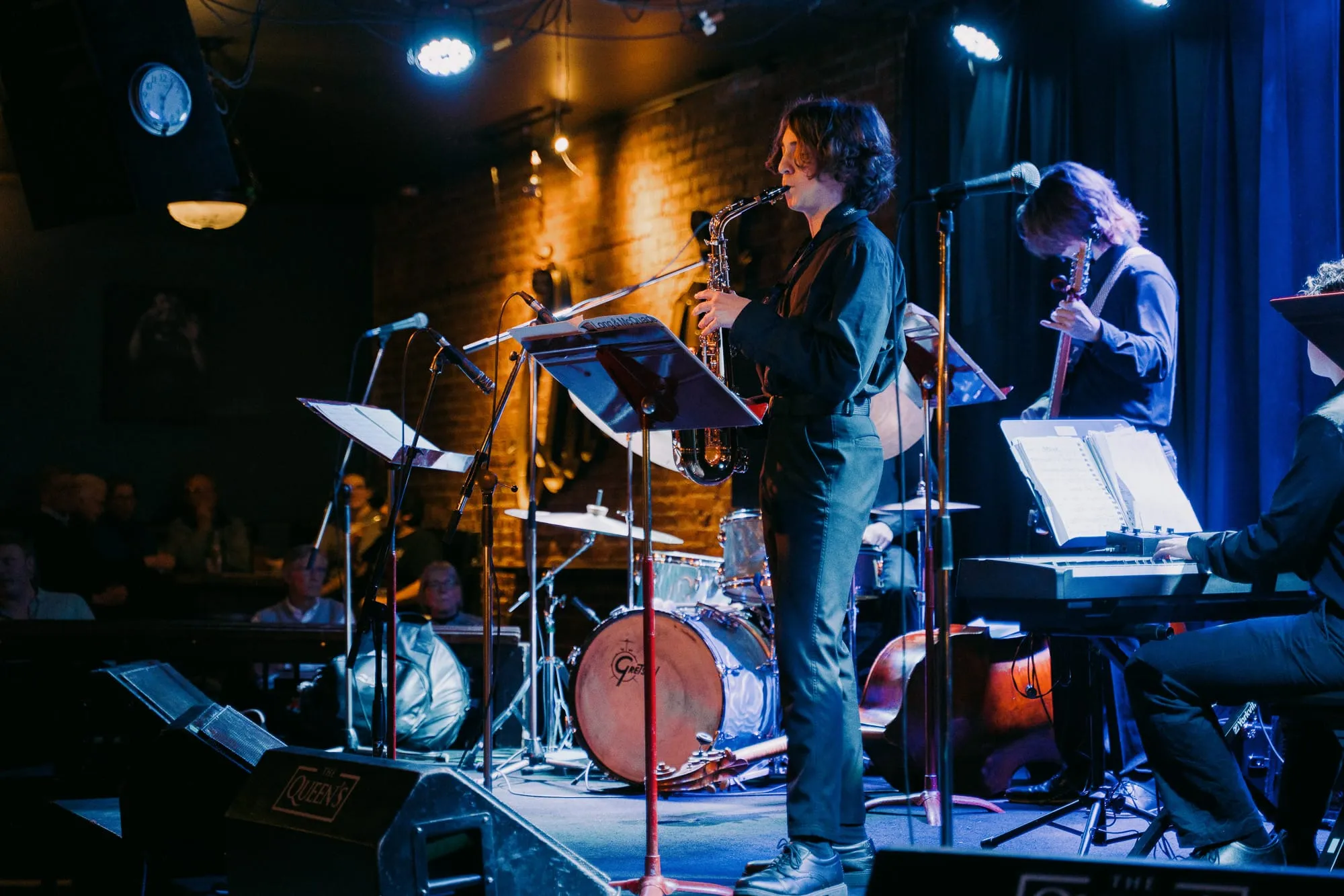 A saxophonist fronts a student band on a club stage
