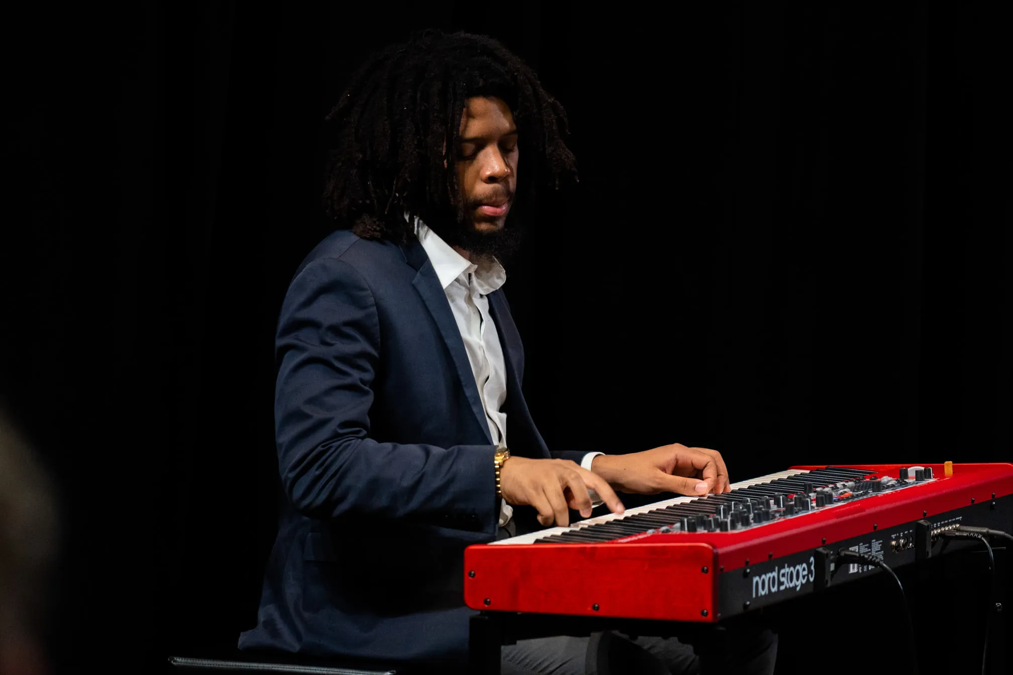 A pianist playing a red stage keyboard